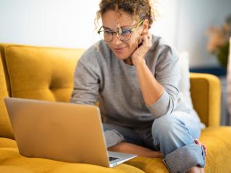 Frau sitzt auf Sofa am Laptop